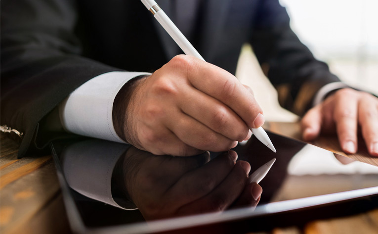 Main d'une personne signant avec un stylet sur une tablette électronique .